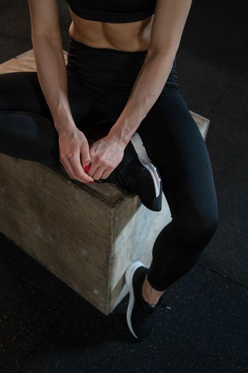 Free Fit woman in black activewear sitting on a plyometric box, showcasing muscular build in a gym setting. Stock Photo