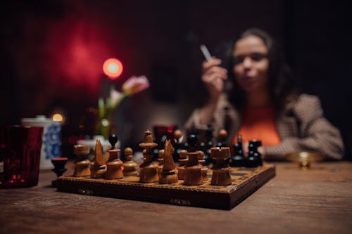 Woman Holding a Cigarette Stick While Playing Chess