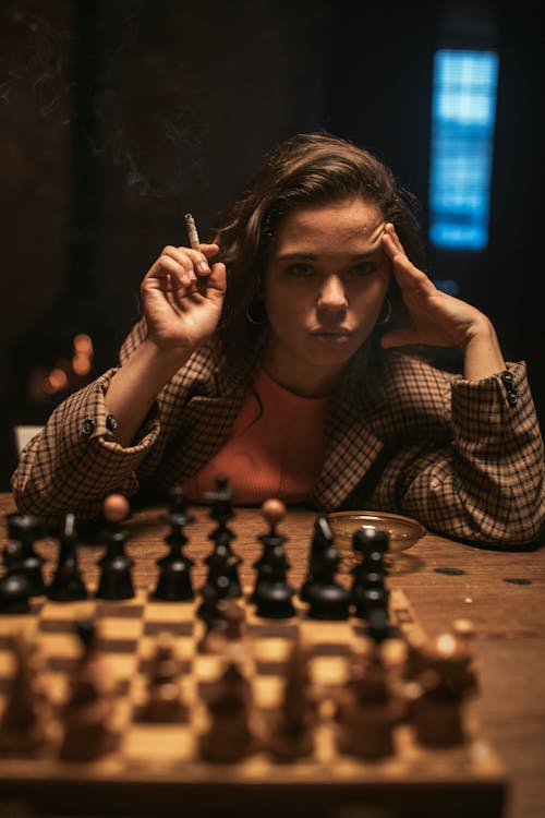 Woman Thinking while Smoking on Table with Chess