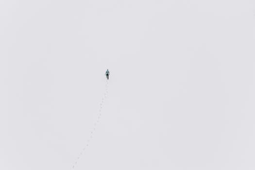 Aerial view of a person walking across a snowy field, leaving footprints behind.