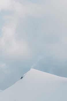Peaceful winter landscape with a snow-covered peak and cloud-filled sky.