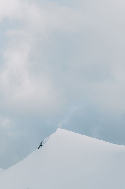 Peaceful winter landscape with a snow-covered peak and cloud-filled sky.