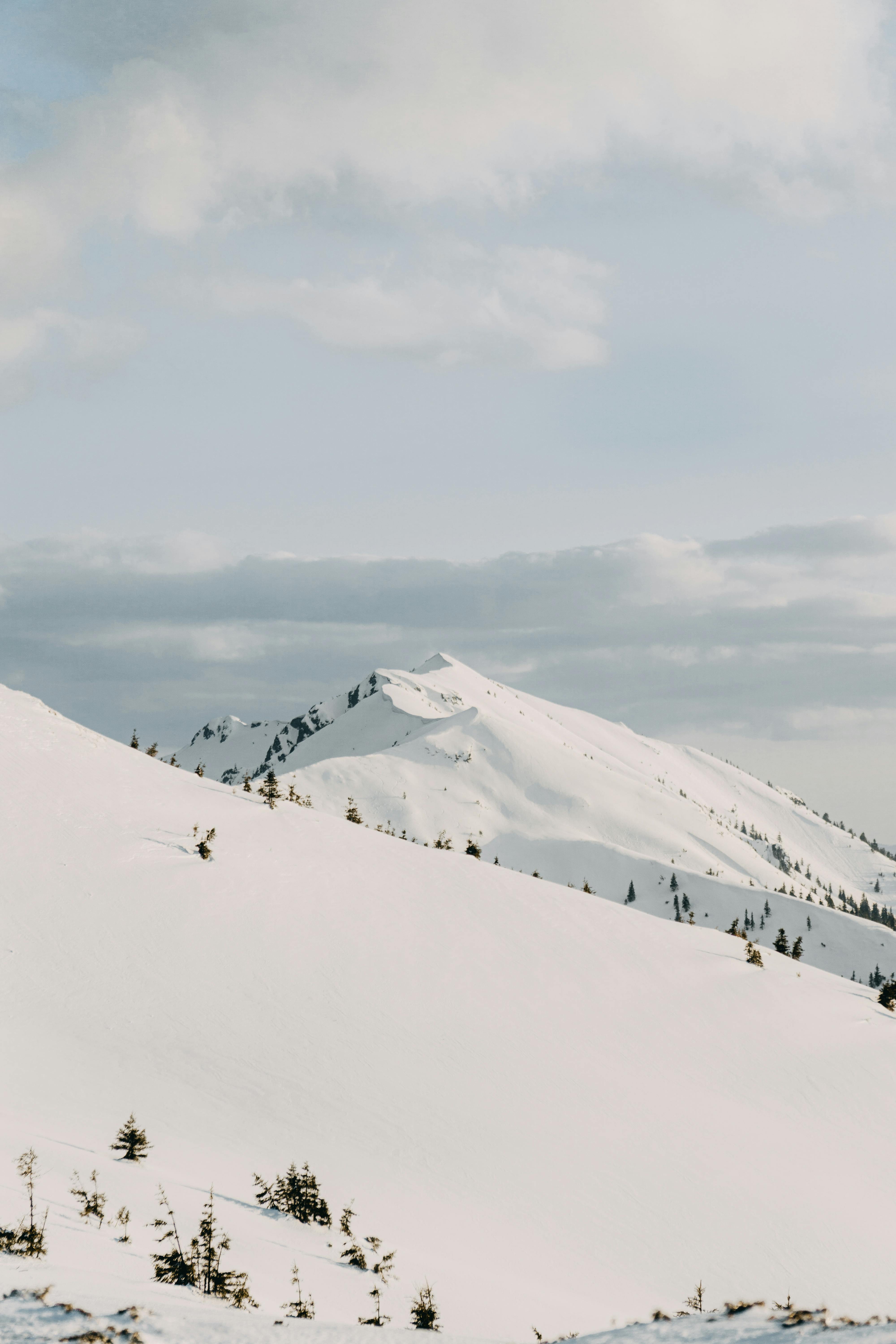 Peaceful winter landscape with snow-covered mountains and cloudy sky.