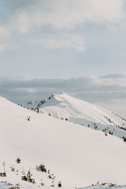 Peaceful winter landscape with snow-covered mountains and cloudy sky.