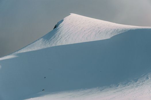 Serene snowy mountain peak with skiers in the distance, capturing the essence of winter adventure.