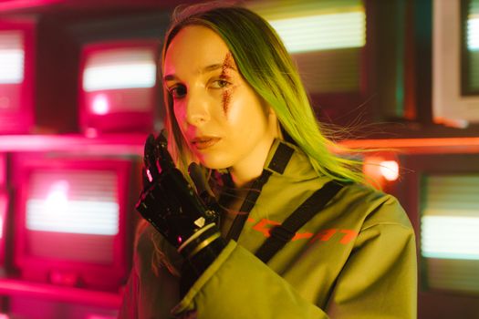 Striking portrait of a woman with green hair and prosthetic hand in a neon-lit room.