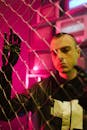 Man Standing Near a Chain Link Fence