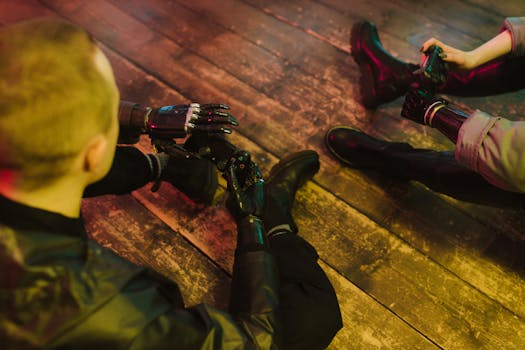Two people with prosthetic hands playing video games on a wooden floor.
