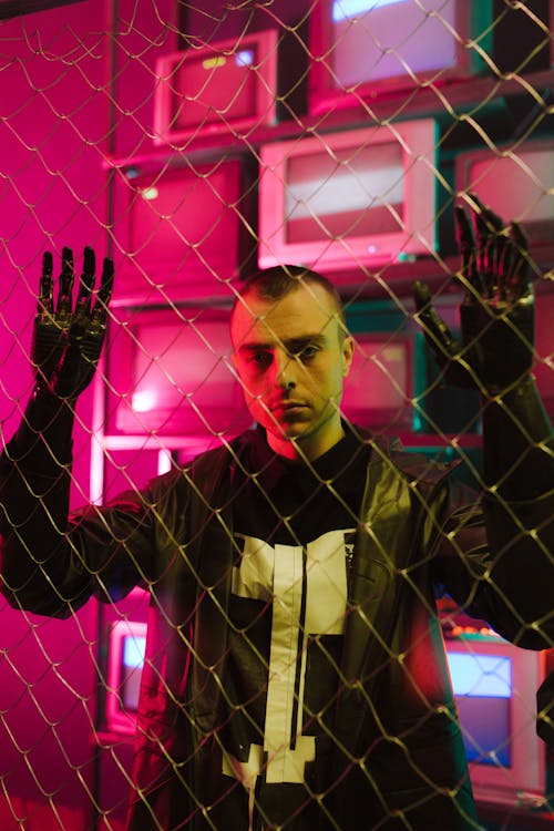 A Man with Prosthetic Hands Holding a Chain Link Fence