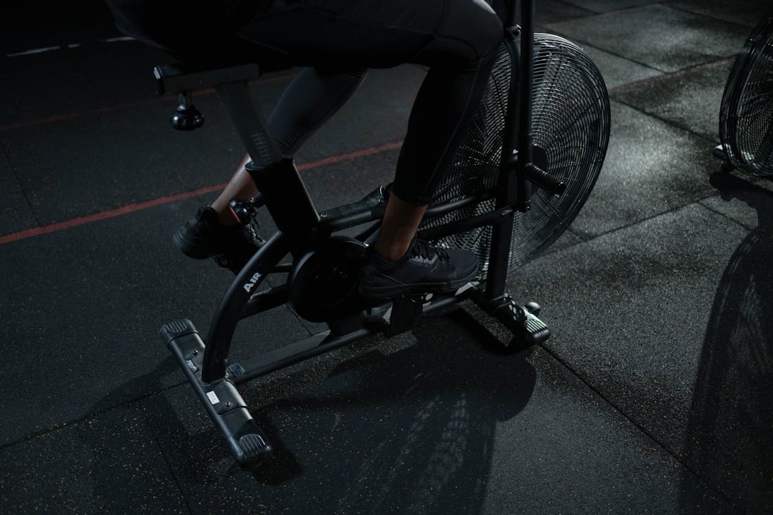 Free Person in Black Pants Using a Stationary Bicycle Stock Photo