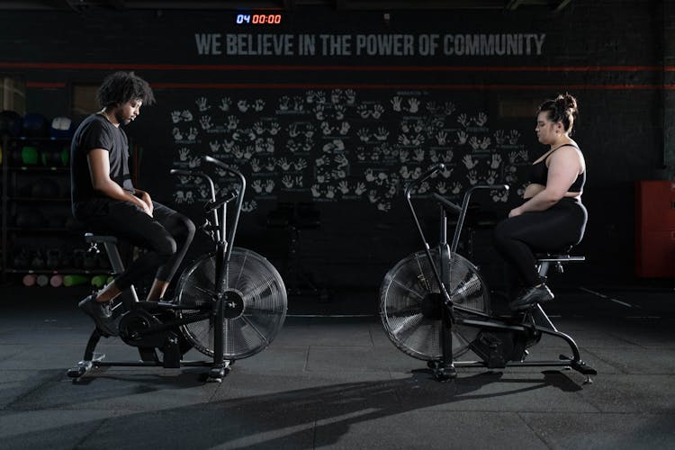 Man And Woman Exercising Using A Stationary Bicycle