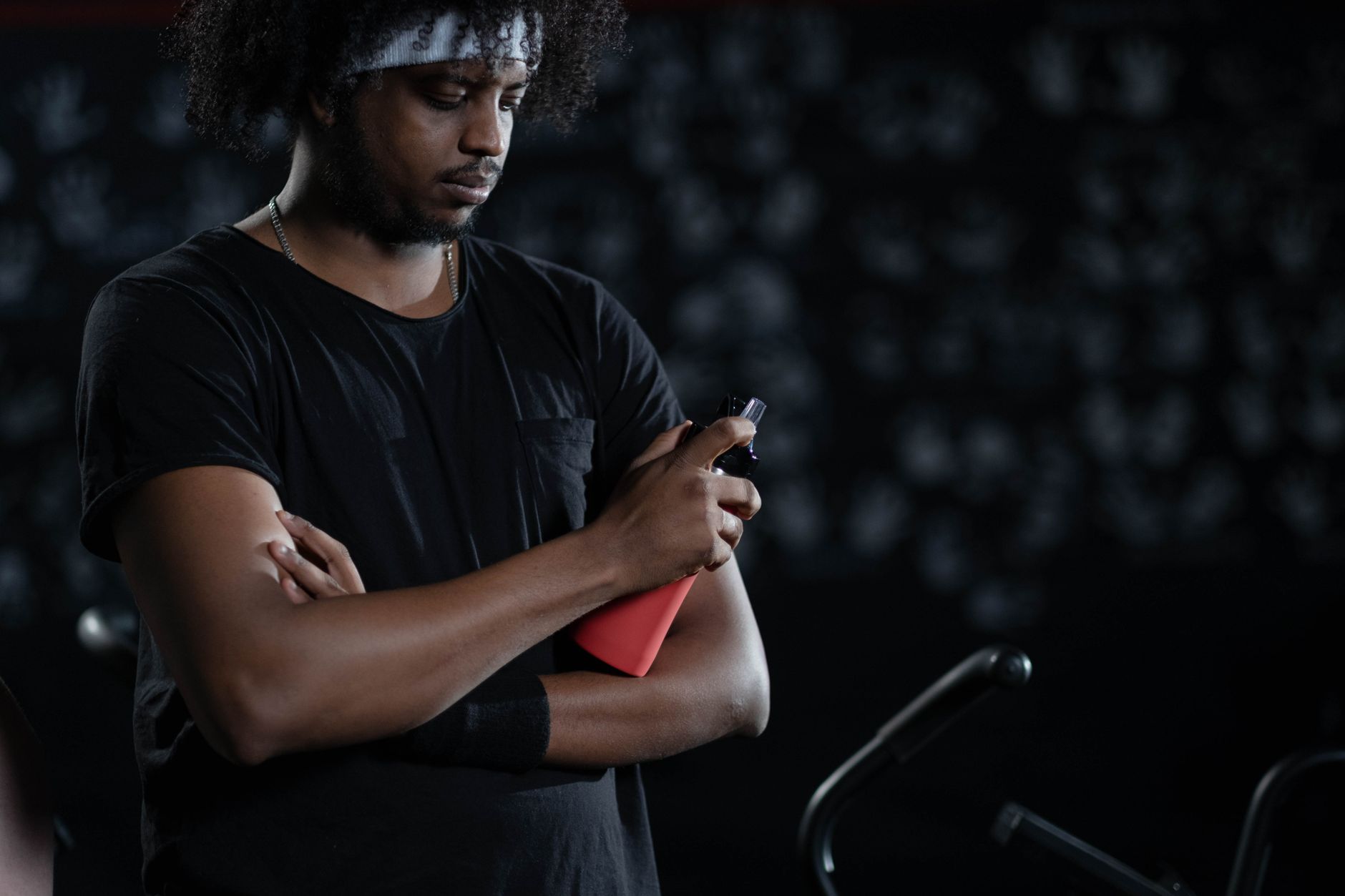 Male athlete with a sports bottle, arms crossed in a gym setting, reflecting focus and determination.