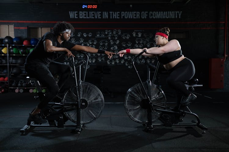 Man And Woman Exercising Using A Stationary Bicycle