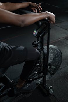 A close-up of a person exercising on a stationary bike in a dimly lit gym setting.