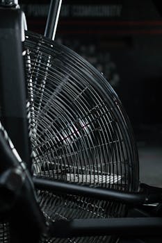 Detailed view of a modern exercise bike's fan in a dimly lit gym setting.