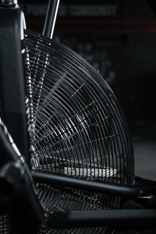 Free Detailed view of a modern exercise bike's fan in a dimly lit gym setting. Stock Photo