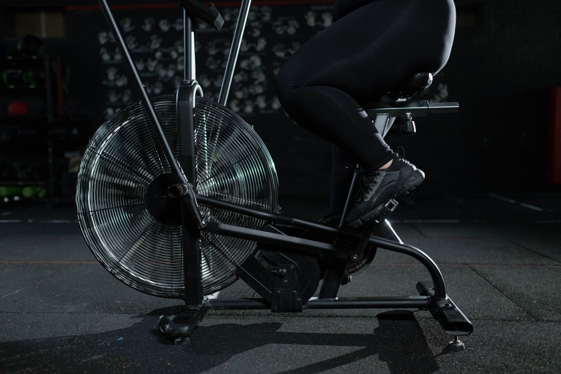 Close-up of a woman exercising on a stationary bike in a dimly lit gym.