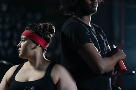 Two diverse adults in activewear, showcasing fitness and body positivity during a workout indoors.