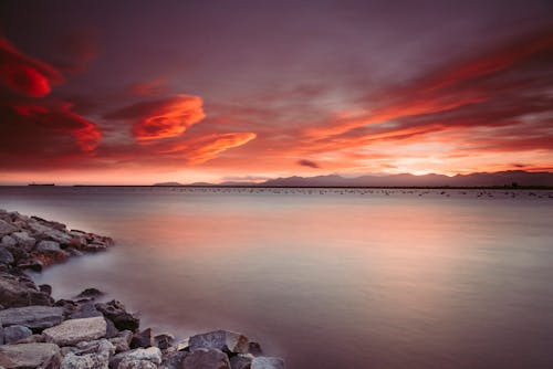 Free Landscape Photography of Rocks Near Body of Water during Sunset Stock Photo
