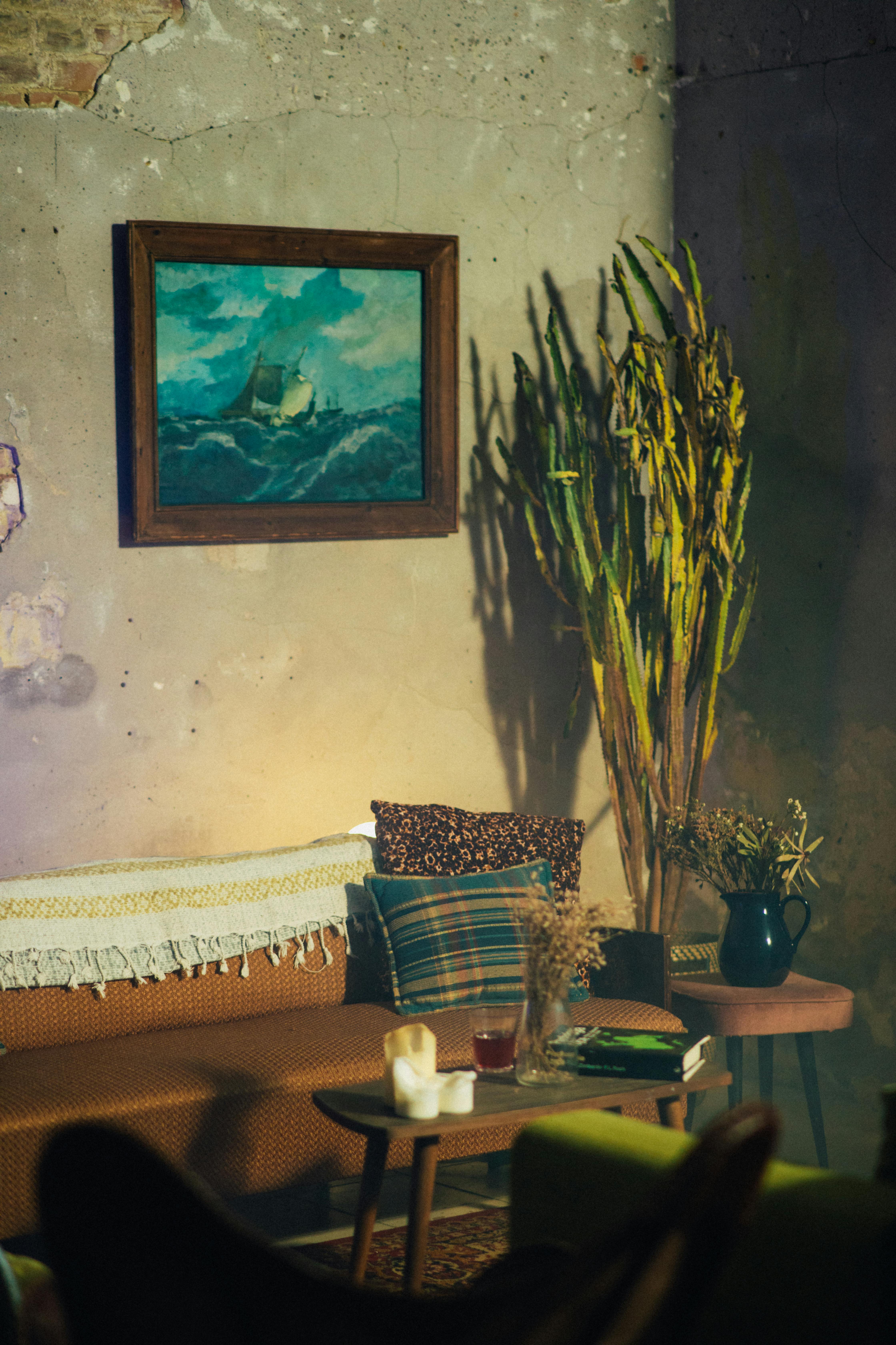 Vintage-style living room with a cozy sofa, painting, and plants for a warm ambience.