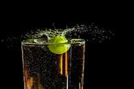 在暗色背景下，一杯清水中葡萄溅起鲜艳的水花