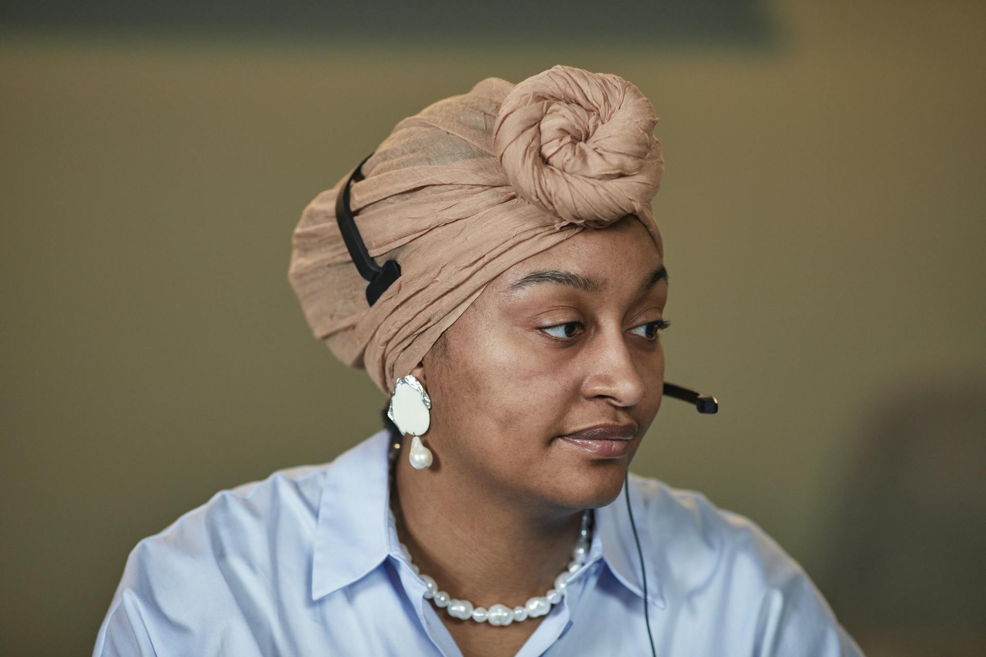 A focused woman in customer service wearing a headset and turban, showcasing professionalism.