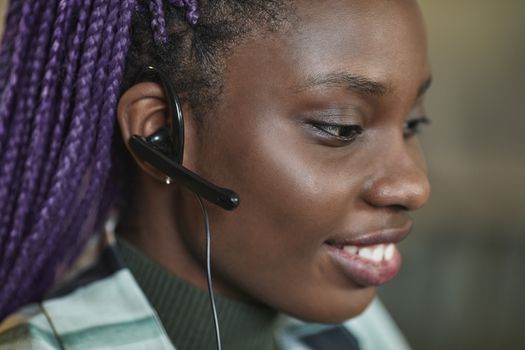 Close-up of a happy call center worker wearing a headset and smiling while working.