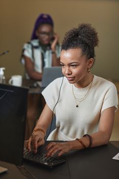 Young female employee working at her desk in a modern call center office environment.