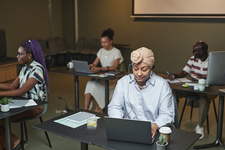 A Woman With A Headwrap Working On Her Laptop