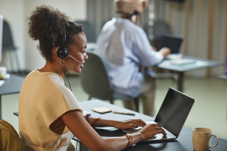 Side View Of A Curly-Haired Woman Using A Laptop While Working In The Office