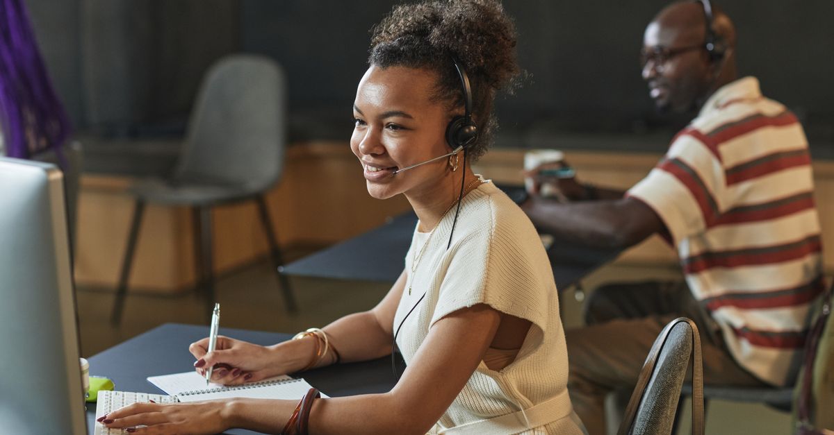 Call centre agent with headset working at a computer — professional call answering services for trade businesses