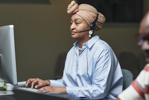 Focused employee in an office setting using a computer and headset.