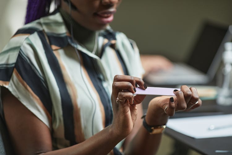 A Woman Sitting While Filing Her Nails 