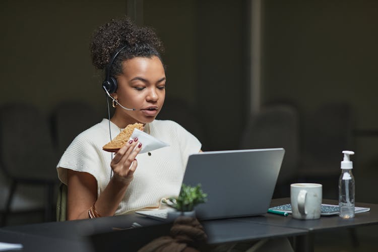 A Woman Eating A Bread While Working