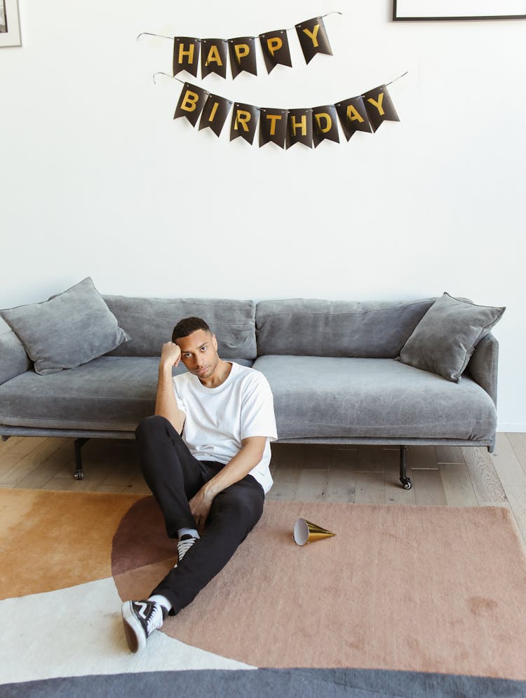 Man Sitting On The Floor Near A Happy Birthday Banner