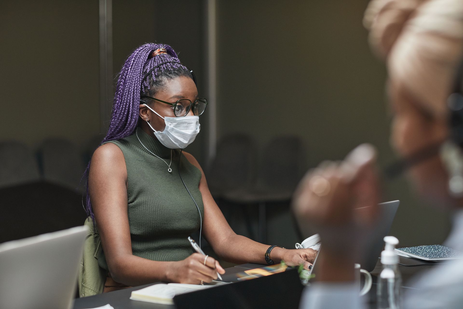 Professional African American woman wearing a mask, working in an office setting.