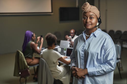 Free Woman with Headset Standing Beside a Group of People at Work Stock Photo