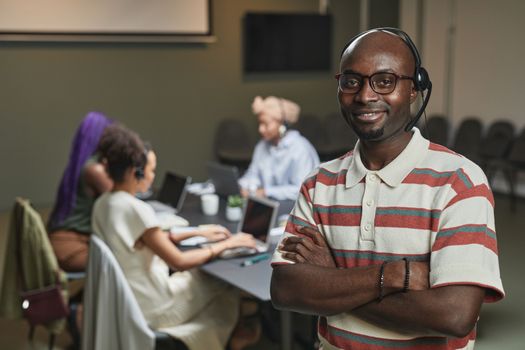Smiling man with headset leading a diverse team in a modern call center setting.