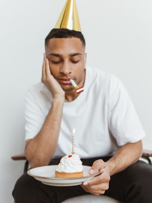 Man in White Crew Neck T-shirt Holding White Ceramic Plate With Cake