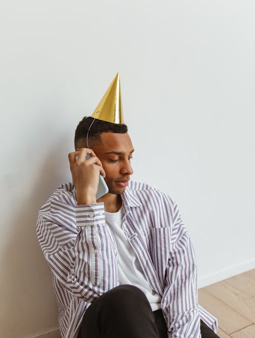 A Man Wearing Party Hat While Using Smartphone 