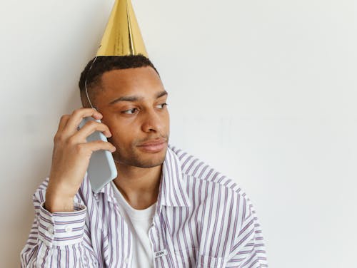 A Man in Party Hat while using Smartphone