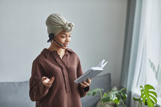 African American woman with headset reading notes in home office, working remotely.