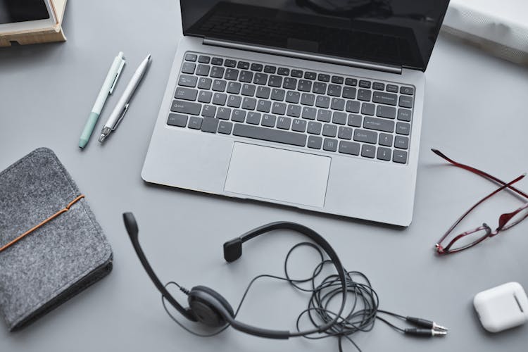 A Laptop Beside Black Headphones