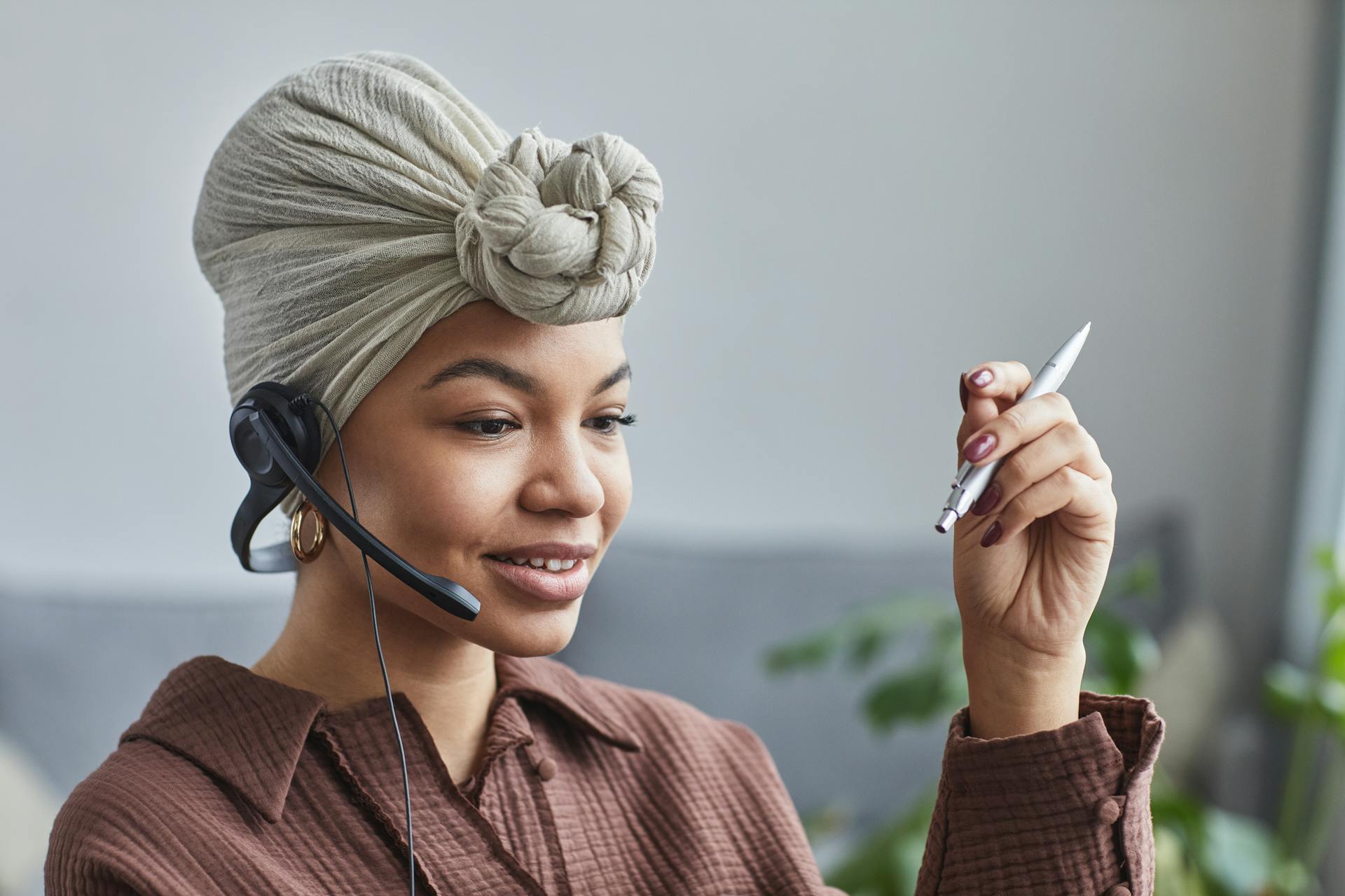 Smiling woman wearing a headset while working at a call center, looking engaged and professional.