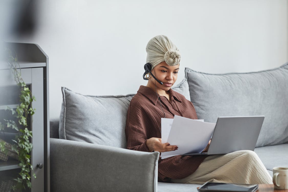 Focused black woman with laptop examining documents