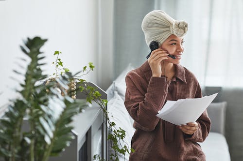 Positive black woman with handsfree headset and documents