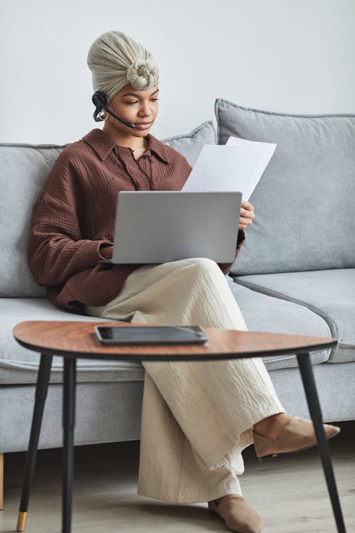 Black woman on couch with documents and laptop