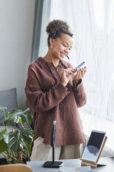Smiling woman talking on smartphone in cozy home office, enjoying a pleasant conversation.