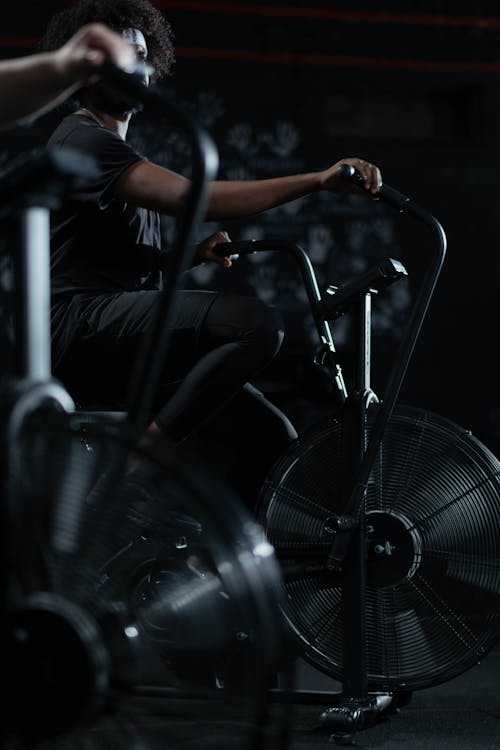 Free Person in Black Activewear Using a Stationary Bicycle Stock Photo