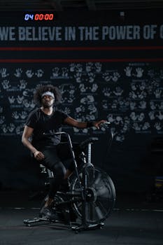 A man working out on a stationary bike in a dimly lit gym setting.
